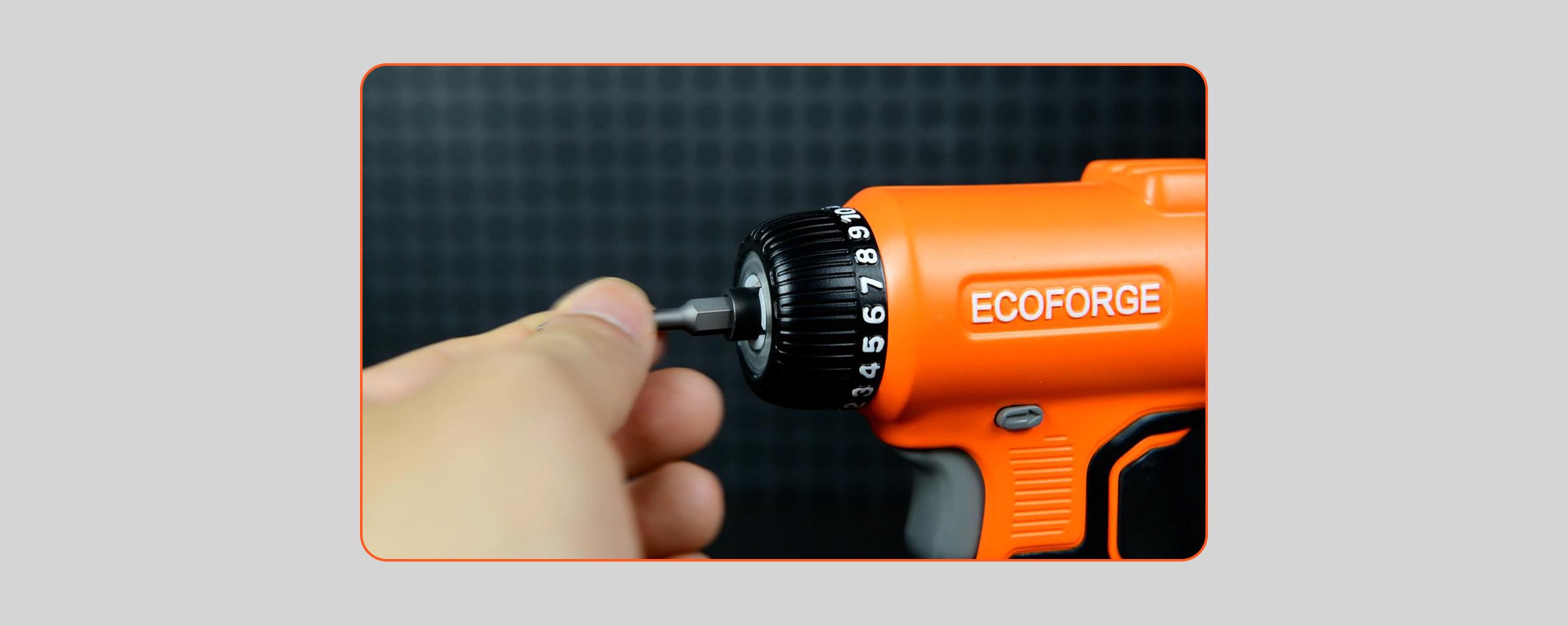 A close-up photograph of a hand inserting a driver bit into the hex chuck of an orange and black ECOFORGE electric screwdriver, showing the quick-loading bit feature against a dark pegboard background.
