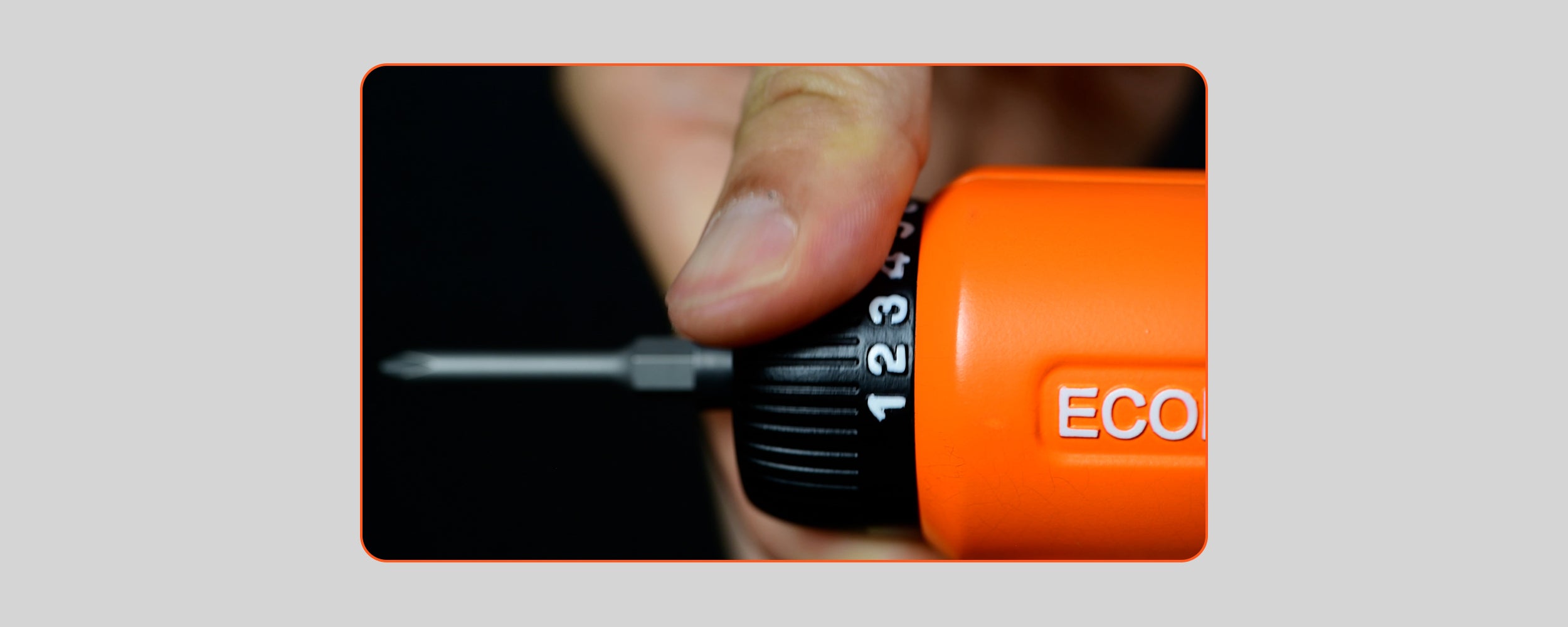 A close-up photograph of a hand adjusting the black numbered torque collar on an orange ECOFORGE electric screwdriver, demonstrating the multi-stage torque selection ring against a dark background.