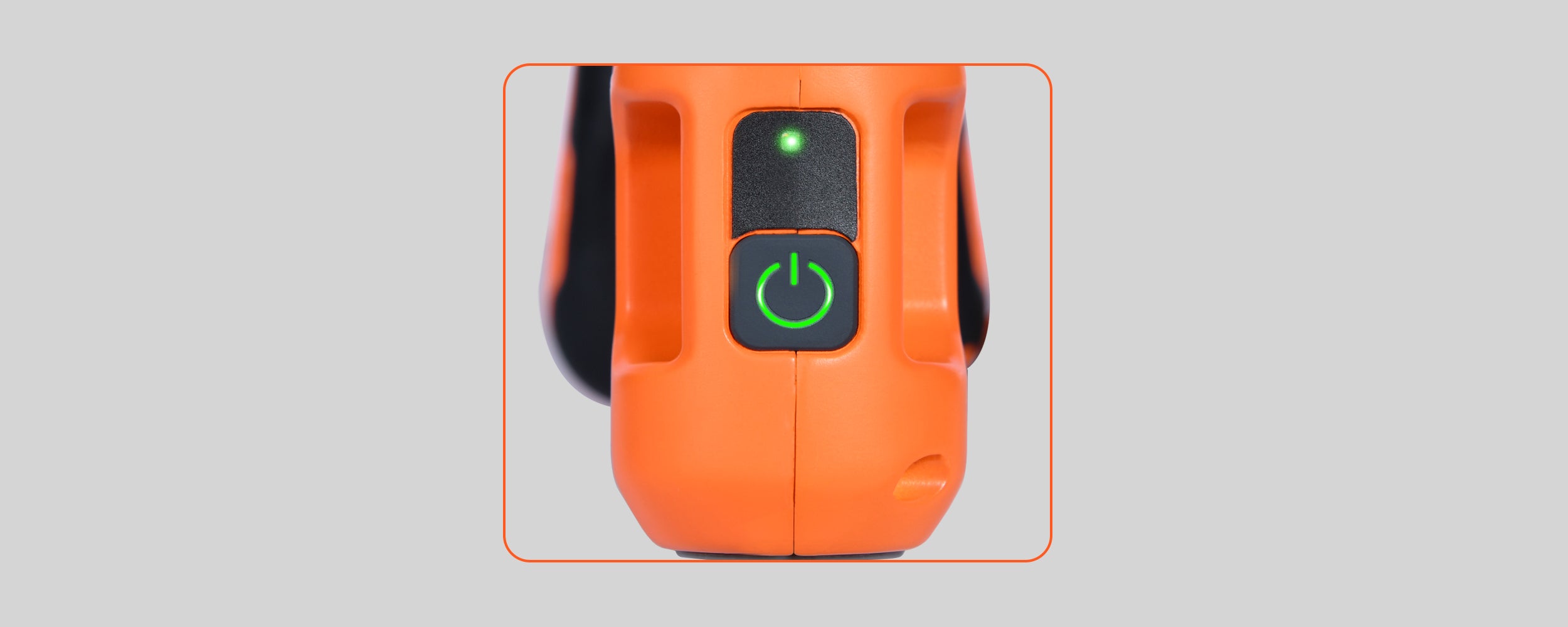 A close-up photograph of the power interface on the orange ECOFORGE tool housing. Set into a dark grey panel, a square power button glows with an illuminated green power symbol, positioned directly below a small green LED indicator light.